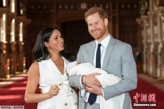 资料图：当地时间2019年5月8日，英国哈里王子和梅根夫妇抱着刚出生的儿子在温莎城堡的圣乔治大厅合影。